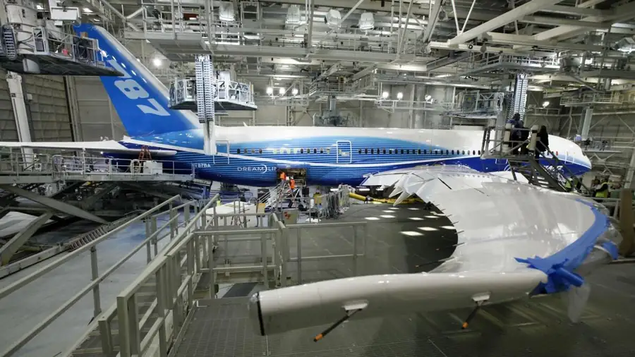 Boeing 787 Dreamliner ZA001 prototype on the final assembly line at Boeing Everett — first 787 airframe in the original blue-and-white Dreamliner livery being prepared in the assembly hangar with composite barrel sections and scaffolding around the fuselage