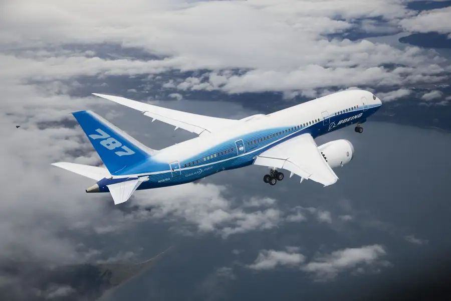 Boeing 787 Dreamliner ZA001 in flight test — first 787 airframe N787BA in Dreamliner blue-and-white livery cruising over the Puget Sound during certification flight testing, three-quarter starboard view with landing gear extended