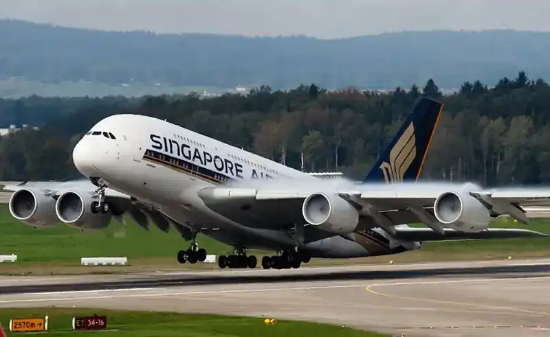Singapore Airlines Airbus A380 lifting off — side view of the world's largest passenger aircraft just after rotation, four engines visible, treeline behind