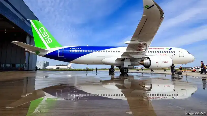 COMAC C919 narrow-body twin-engine airliner outside hangar at Shanghai — green & blue Chinese livery on B-001A airframe