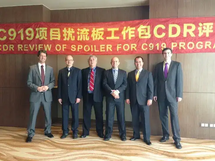 Six-engineer leadership team standing in front of red CDR Review banner for C919 Spoiler programme at the Critical Design Review meeting in China — bilingual Chinese / English banner reads 