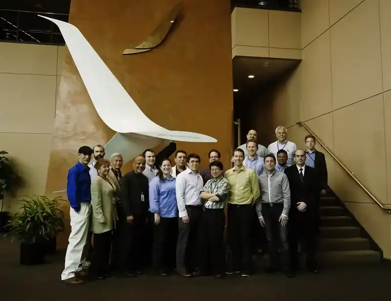 Boeing engineering team assembled beneath the Blended Split Winglet (Future Development Program) display sculpture in the company lobby — group portrait