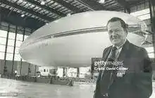 Reg Hilsden — Airship Industries designer standing in front of airship envelope in hangar