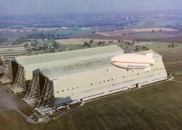 Cardington airship sheds with an Airship Industries Skyship moored alongside, aerial view