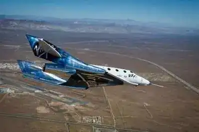 SpaceShipTwo VSS Unity in flight over Mojave desert — banking turn with feather mechanism stowed