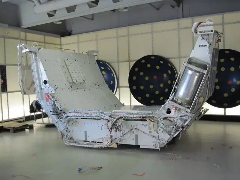 Spacelab Igloo on display in a museum hangar — pressurised cylindrical structure with attached frame and FRAME-labelled instrument tower. The Igloo housed subsystems (power, command, data) for Spacelab pallet-only missions when no habitable module was flown.