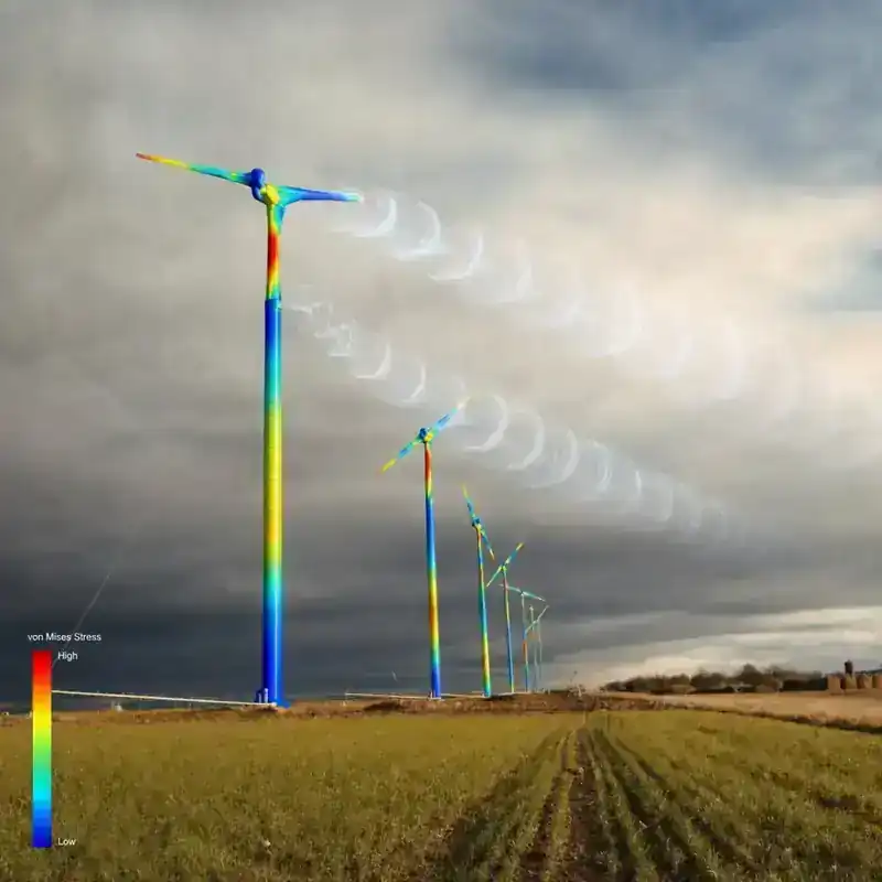 Finite element von Mises stress analysis overlay on Carter wind turbines in their installed field setting — red-yellow stress concentration visible at the rotor nacelle and tower-top junction, blue-green low-stress tower stem, with streamlined helical wake vortex shedding visualisation extending downwind from each rotor