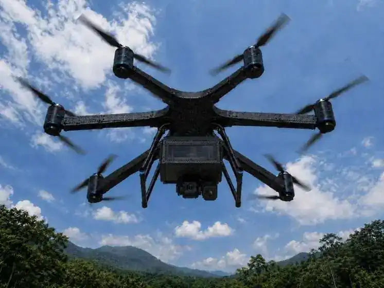 NXYWING hexacopter UAV in flight with camera payload against blue sky and mountain landscape