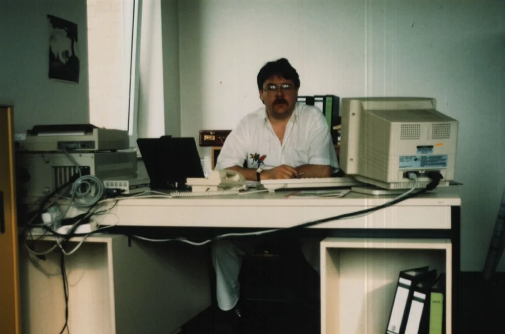 Steve at his desk in the Pierburg Neuss office during Eurofighter and EJ200 development — 1990s workstation with CRT monitor, laptop, telephone and dot-matrix printer